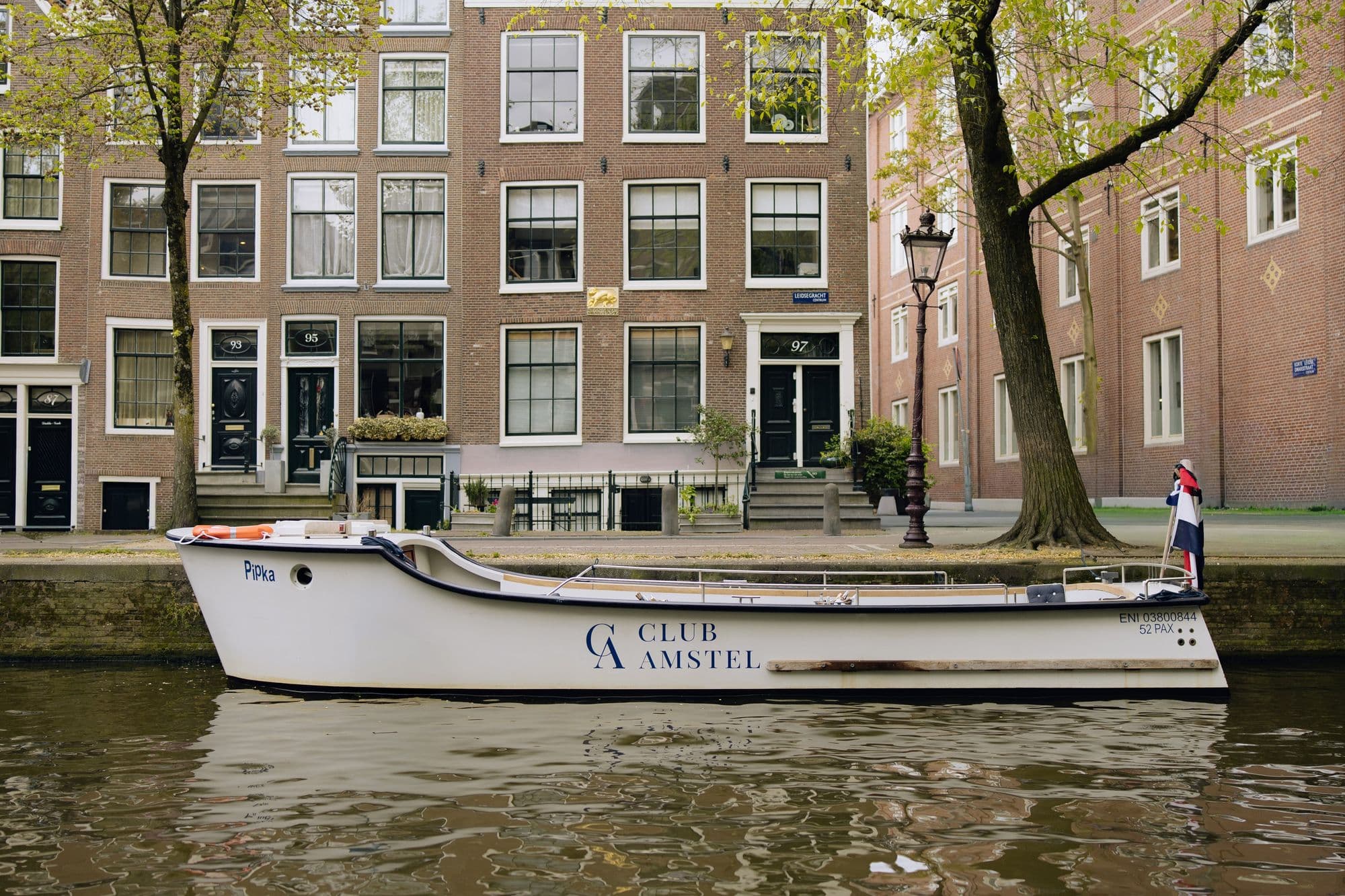 Klassieke bakdekker van Club Amstel afgemeerd aan een Amsterdamse gracht