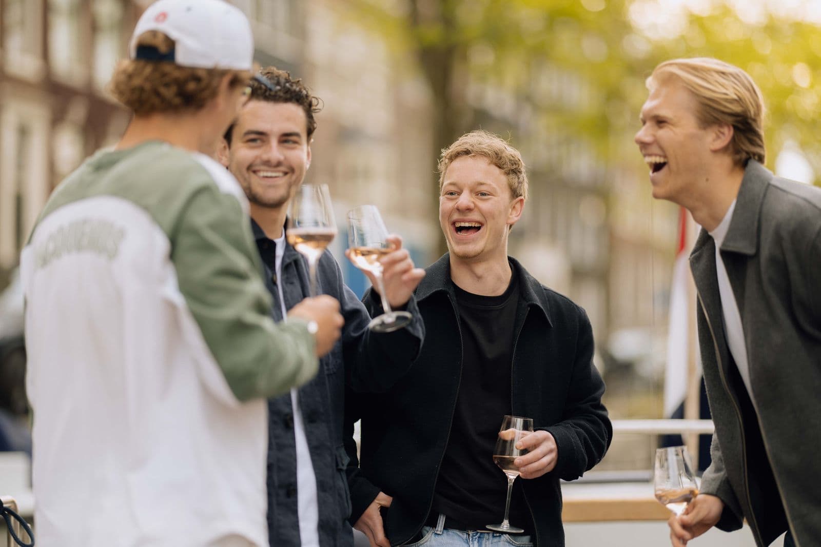Vrienden lachen met wijn op de grachten
